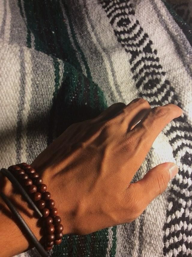 a person's hand on top of a rug with beads and leather bracelets