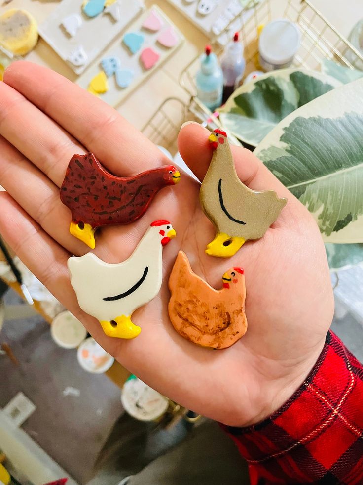 two little chickens and one big chicken are in someone's hand with fake food