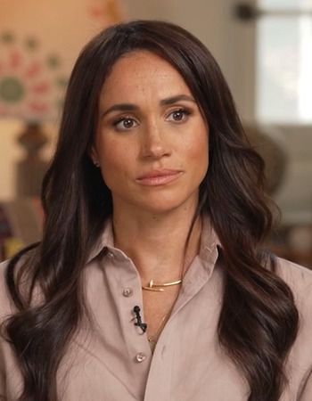 a woman with long dark hair wearing a tan shirt