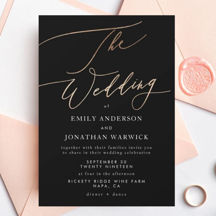 a black and gold wedding card with the word, the wedding on it next to some pink envelopes