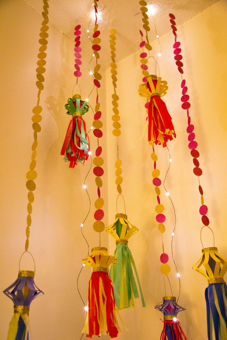 several colorful tassels hanging from the ceiling with lights on them and beads attached to it