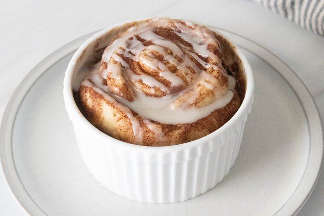 a white plate topped with a cinnamon roll covered in icing on top of it