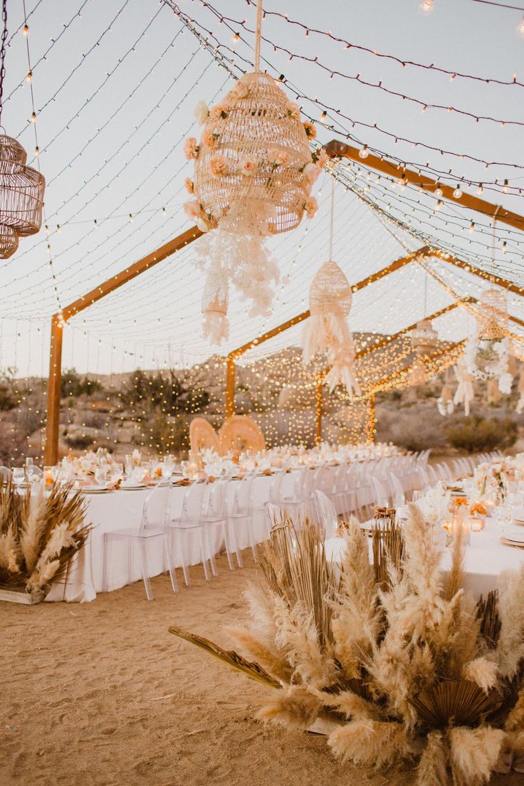 an outdoor dining area with tables, chairs and hanging chandeliers in the desert