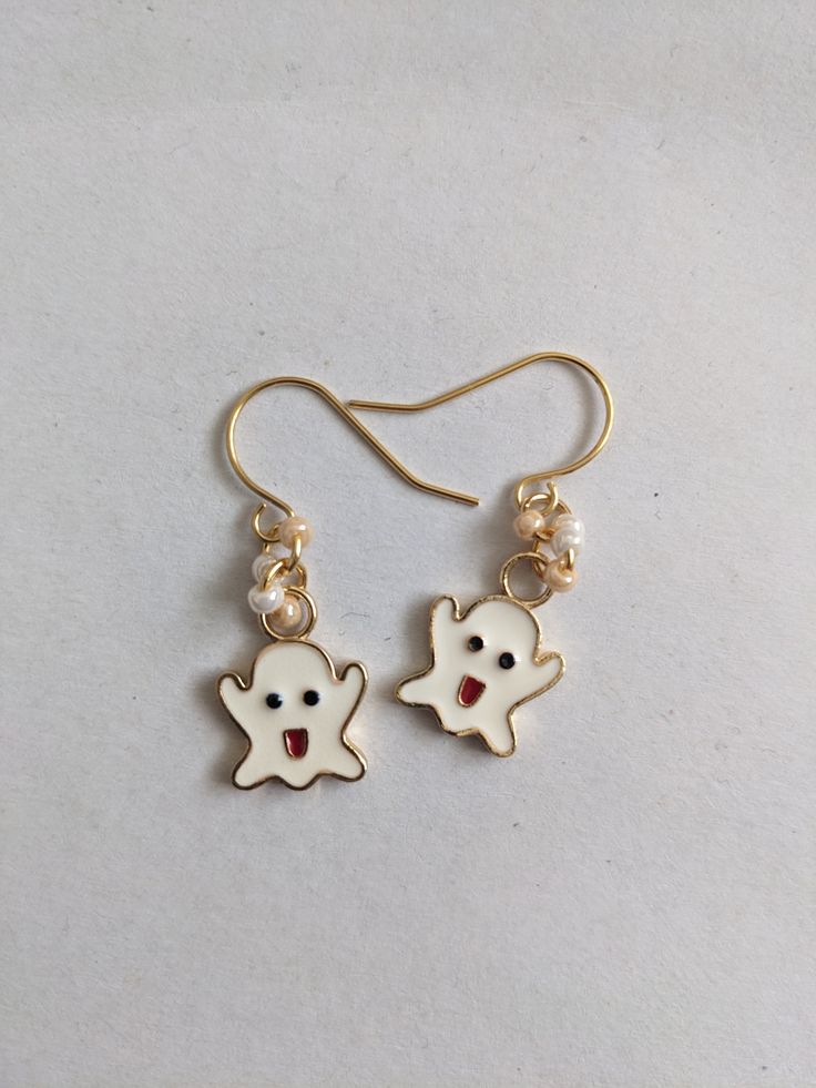 A cute and fun pair of ghost earrings, perfect for Halloween. The white enamelled ghost design, is on a 24k gold plated colour charm, attached to 24K gold plated ear wire hooks, with additional beads added. Great to keep as a fun pair of spooky, Halloween earrings, or to gift to ghost loving friend. Supplied in a gold organza pouch. Spooky White Earrings For Halloween, White Enamel Jewelry For Party, White Spooky Earrings For Party, Spooky White Earrings For Party, Playful Halloween Earrings As A Gift, Playful Halloween Earrings For Gift, Playful Halloween Earrings For Gifts, Fun Nickel-free White Earrings, White Drop Earrings For Halloween