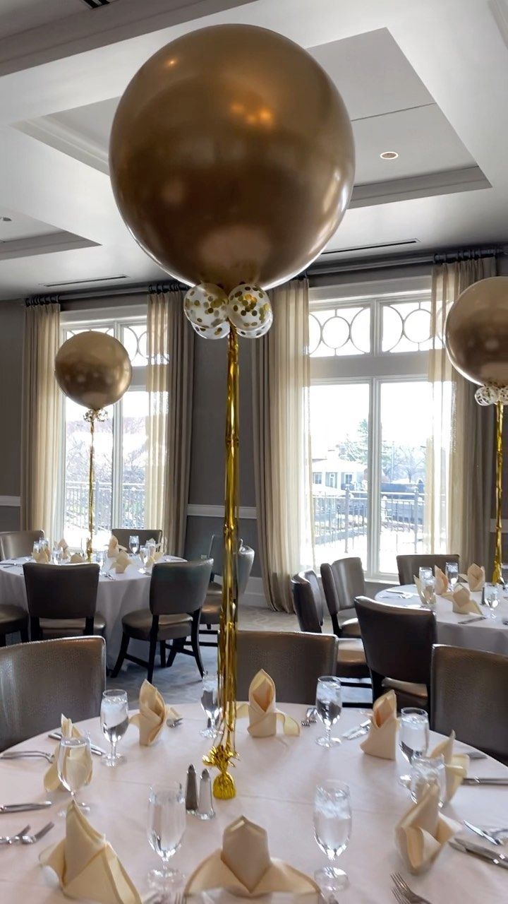 the table is set with silver and gold plates, napkins, and large balloons