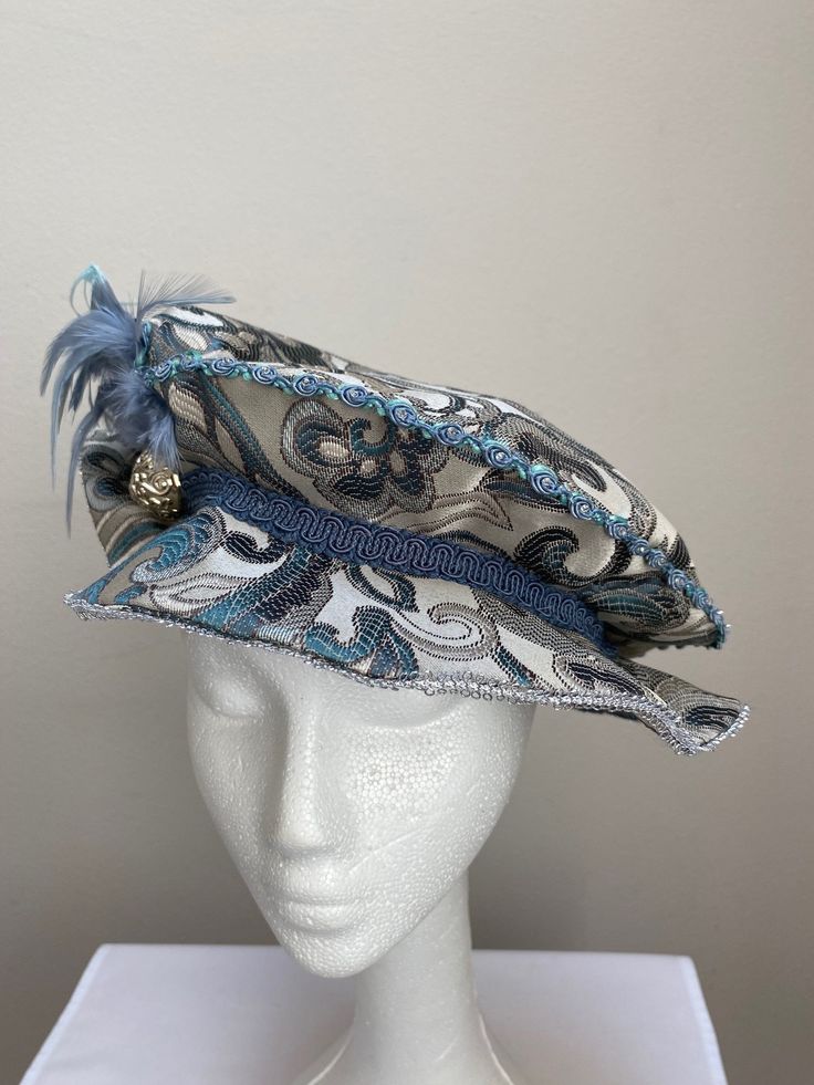 New women's Renaissance Medieval Elizabethan Victorian blue and grey brocade brim hat cap. This stunning brim hat is embellished with a matching side feather cluster secured with a gold broach. Under lining. Brim is 2 " wide secured by a blue gimp trim. Great for your next theme party, stage production or Renaissance Faire. Sales final. New not worn. Adjustable High Crown Blue Costume Hats And Headpieces, Ceremonial Blue Adjustable Hat, Adjustable Blue Ceremonial Hats, Blue Costume Hat For Carnival, Adjustable Blue Costume Hats And Headpieces, Brimmed Hats For Kentucky Derby Costume, Stage Production, Costume Cosplay, Costume Hats