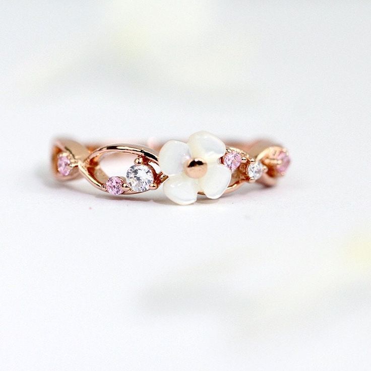 A beautiful rose gold wreath ring featuring a mother of pearl flower adorned with CZ diamonds in white and pink! The gems are exquisitely and securely hand-set by experienced artisan.  Wear this every day and especially with the matching necklace, a classic white, blue, or black little dress for the most dainty look!  ♥ Perfect gift for you and your loved one! ♥ Materials:  - 925 Sterling Silver in Rose Gold - Mother of Pearl - CZ diamond Dimensions:  - 4mm Mother of Pearl Flower  [The Materials] All products are made with high quality hypoallergenic nickel-free  925 real silver in 14k, 18k or rose gold finish. Unlike the thin plated silver or plated gold ones which you would normally find in the market, they will stand the time of wear and would be like new again after a simple polish! Rose Gold Flower-shaped Cubic Zirconia Rings, Rose Gold Flower-shaped Rings With Cubic Zirconia, Rose Gold Cubic Zirconia Flower Ring As A Gift, Rose Gold Cubic Zirconia Flower Promise Ring, Rose Gold Wreath, Black Little Dress, Pearl Wreath, Wreath Ring, Wreath Rings