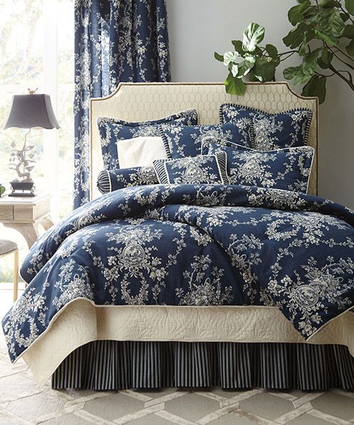 a blue and white comforter set with flowers on it in front of a window