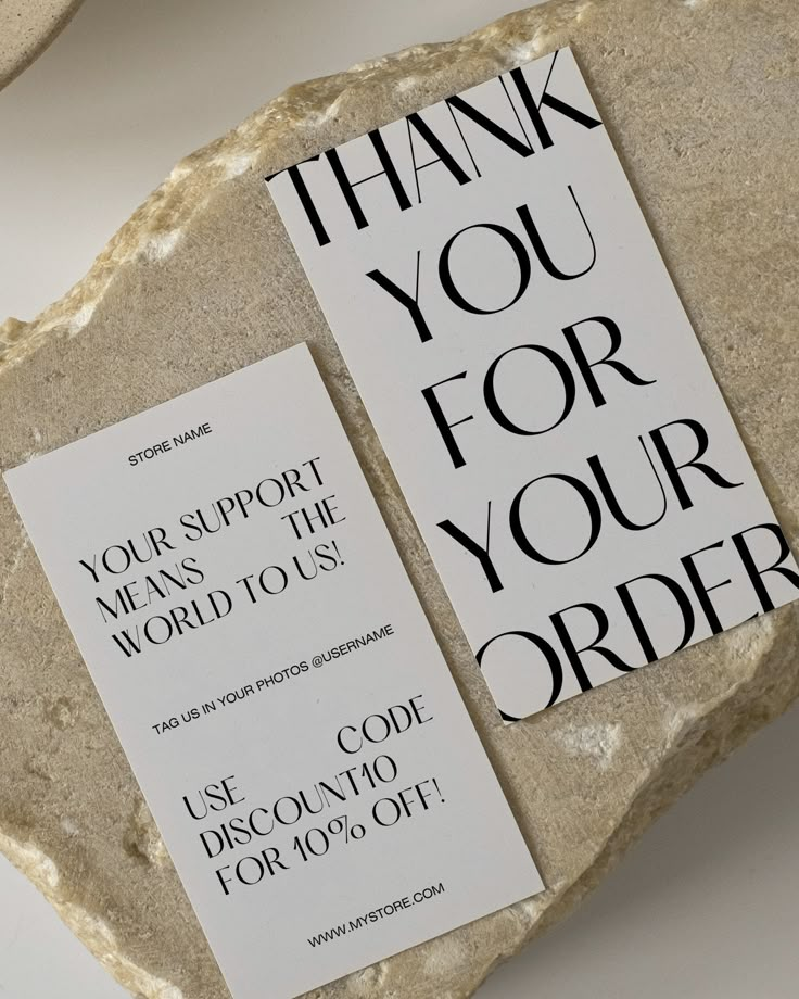 two thank you for your order cards sitting on top of a rock