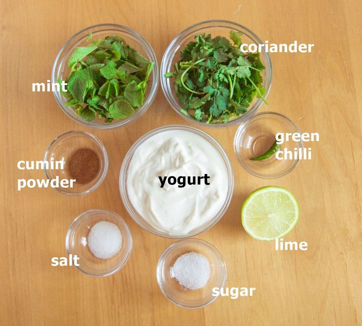 the ingredients to make yogurt sit in bowls on a wooden table with limes