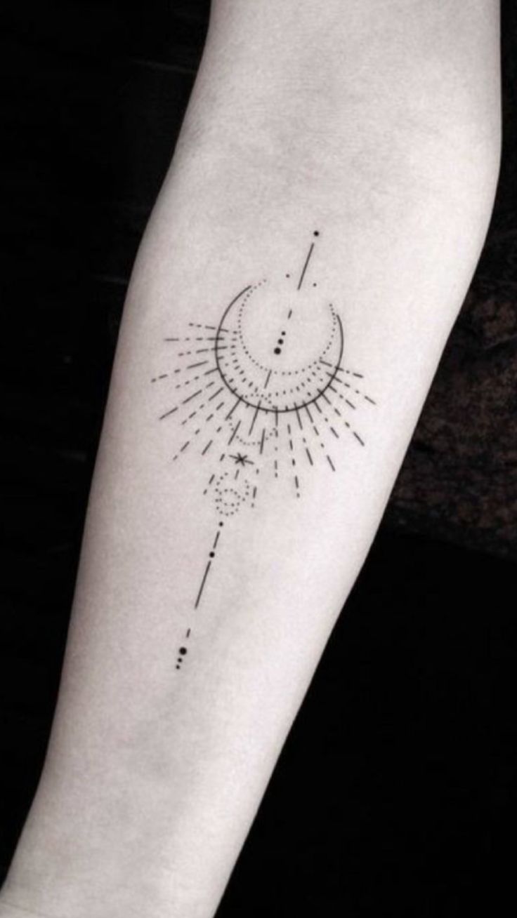 a small sun and moon tattoo on the left arm, with stars in the background