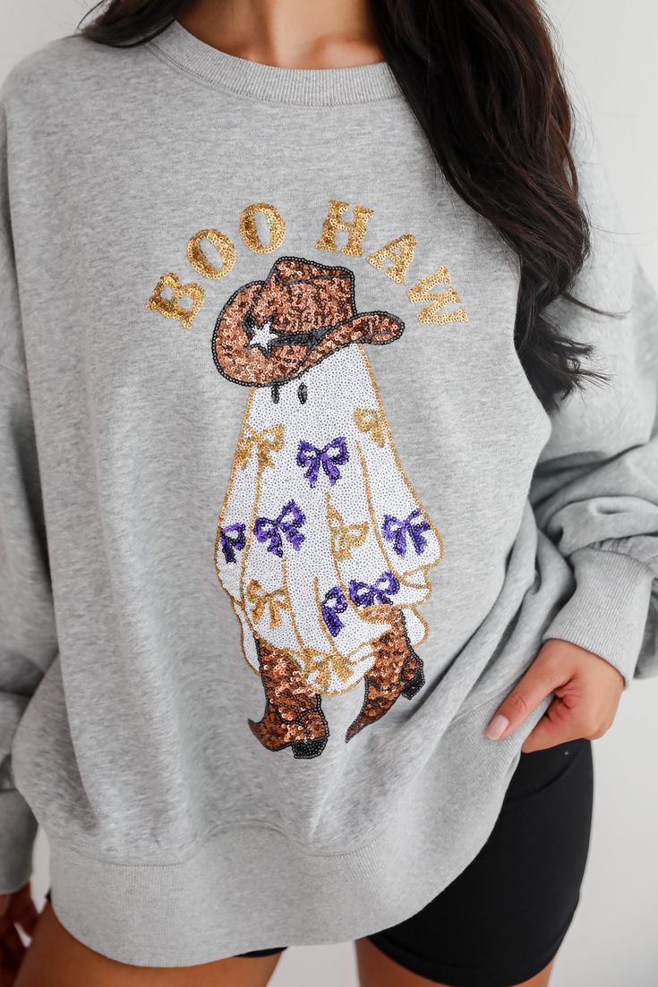 The Boo Haw Sequin Sweatshirt is a fun and festive piece that adds a playful touch to your casual wardrobe. Made from soft, cozy fabric, this sweatshirt ensures comfort and warmth for those chilly days. The heather grey background provides a versatile base, while the whimsical ghost graphic adorned with shimmering sequins and the cheeky "Boo Haw" message create a standout look that's perfect for Halloween or adding a bit of festive flair year-round. The relaxed fit and classic crew neckline make Relaxed Fit Holiday Sweatshirt For Fall, Fall Holiday Cotton Sweatshirt, Cotton Sweatshirt For Fall Holiday, Ghost Graphic, Kimono Outerwear, Sequined Sweatshirt, Fall Flannel, Casual Bodysuit, Brunch Dress