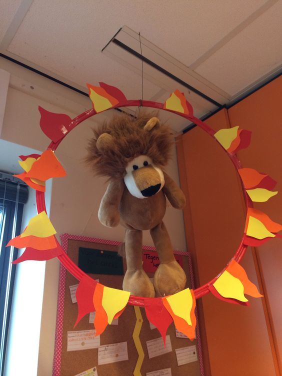 a stuffed animal hanging from the ceiling in front of a mirror with leaves on it