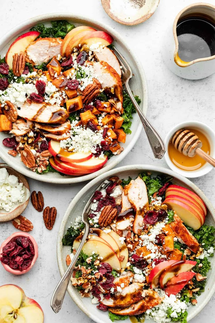 two bowls filled with apples, chicken and pecans next to some cups of coffee