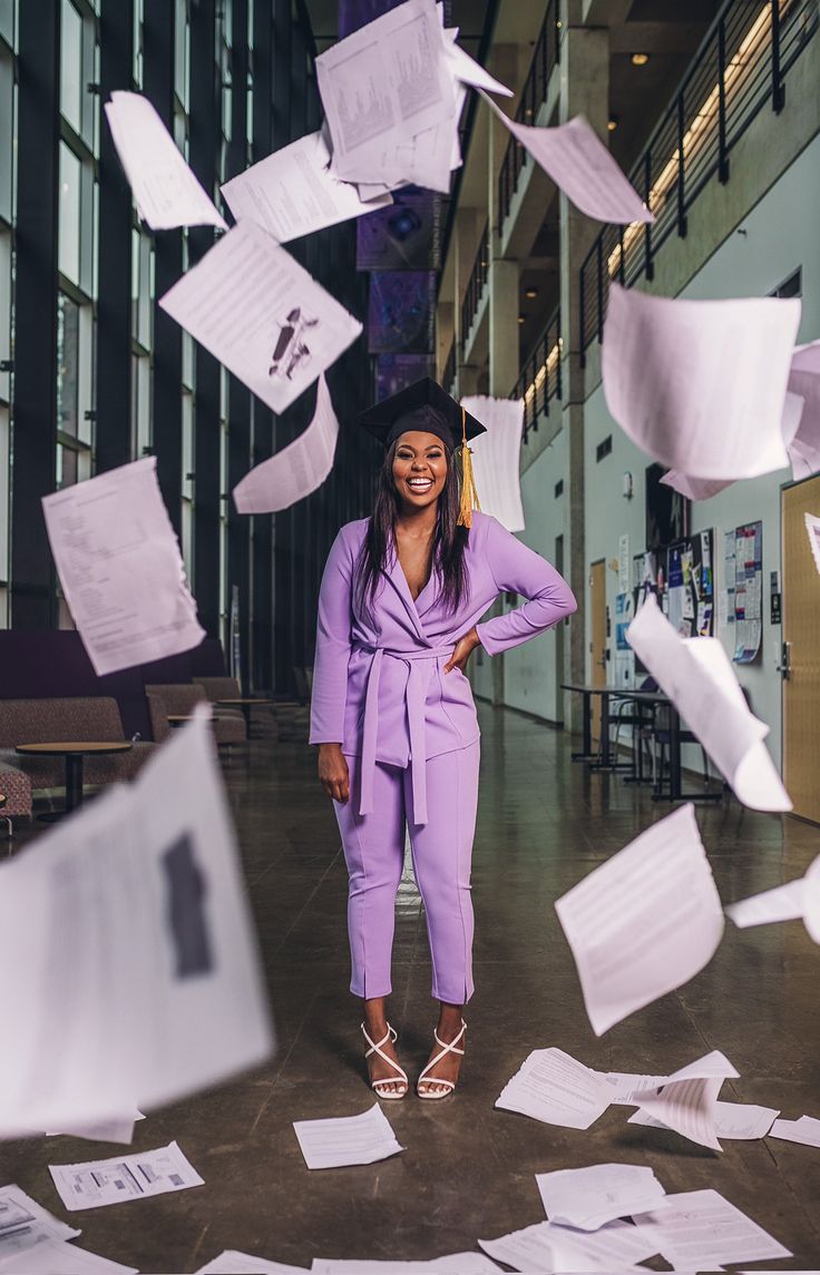 a woman standing in front of papers falling from the ceiling with her hands on her hips