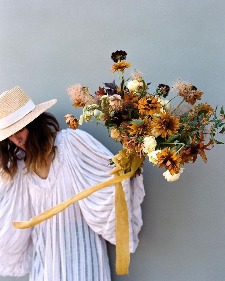 a woman wearing a straw hat holding a bouquet of flowers