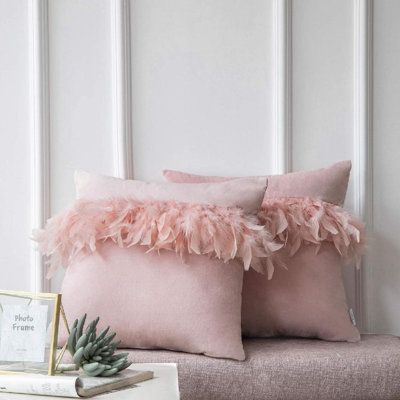 two pink pillows with ruffled edges sit on a bench in front of a white wall