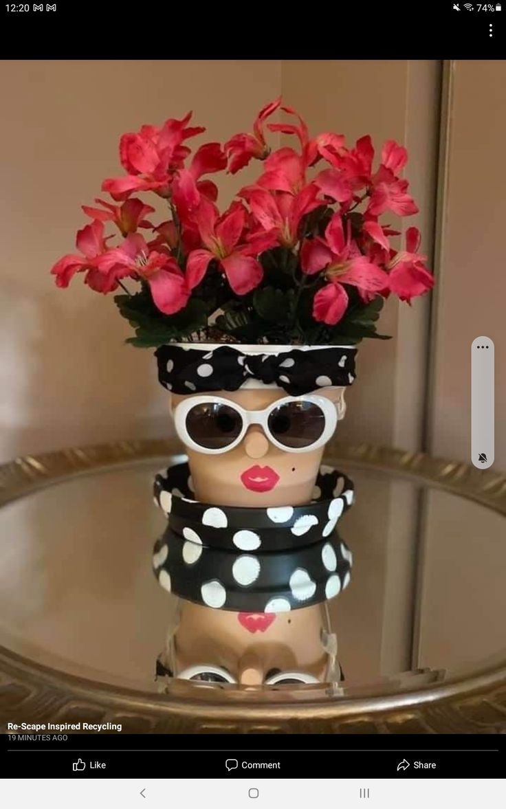 a vase with flowers and sunglasses on top of a glass table in front of a mirror