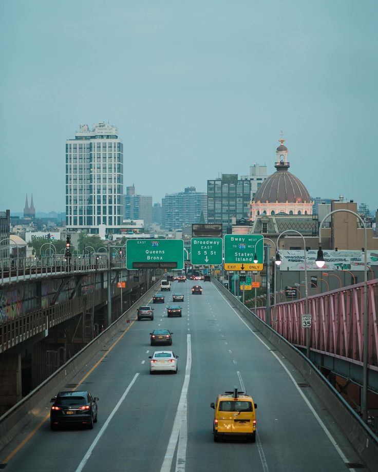 cars are driving down the highway in front of tall buildings and skyscrapers on either side