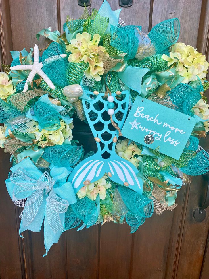 a wreath that has been decorated with blue and yellow flowers, seashells and starfish