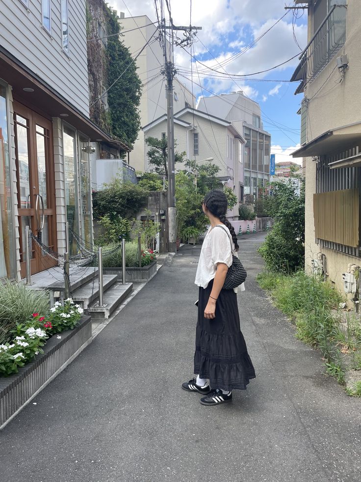 a woman is walking down the street wearing a black dress and carrying a backpack on her back