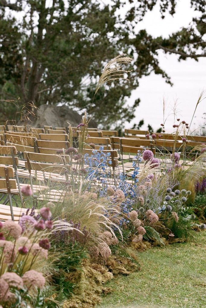 a row of wooden benches sitting next to each other on top of a lush green field