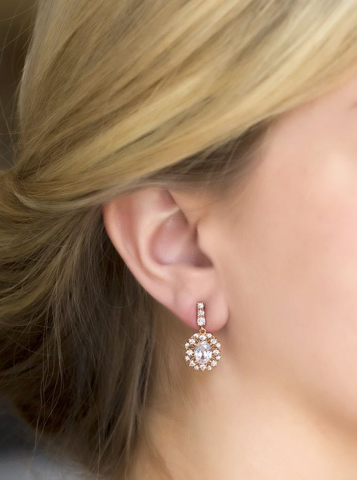 a close up of a woman's ear wearing gold and white earrings with flowers on them