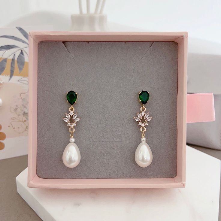 * DETAILS * - Emerald Crystal Glass Post Earrings - Aquamarine Crystal Glass post Earrings  - Teardrop Shaped Synthetic White Pearls  Metal: Bright / shiny gold plated brass 🎁A designer pull drawer pink gift box is available when the gift wrapping option is chosen. ------------------------------------------ * CARE TIPS * ⭐️TO PREVENT TARNISH: Keep your jewellery in airtight plastic bags. It won't tarnish if it isn't exposed to air. The worst place to leave your jewellery is in a steamy bathroom. Wipe with a soft cloth after wearing. - Perfumes: Be sure any perfume or lotions are completely absorbed into skin. - Hair products: Apply all hair products before putting on jewelry. - Swimming: Remove all jewelry before swimming or getting into hot tubes. - No sunlight: Store away from heat, dir Classic Green Earrings For Wedding, Green Teardrop Pearl Earrings For Wedding, Green Dangle Clip-on Earrings For Wedding, Green Drop Pearl Earrings For Wedding, Elegant Green Clip-on Earrings For Wedding, Green Clip-on Earrings For Wedding, Elegant Green Pearl Drop Bridal Earrings, Green Clip-on Wedding Earrings, Pink Gift Box