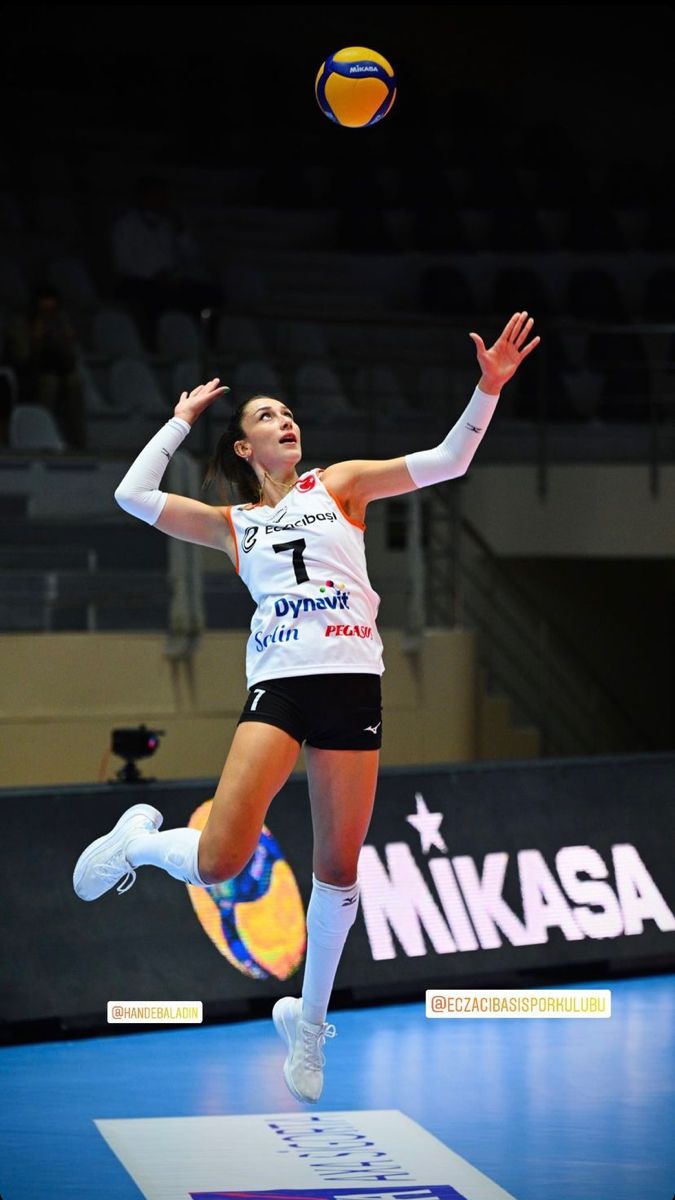 a woman jumping in the air to hit a volleyball