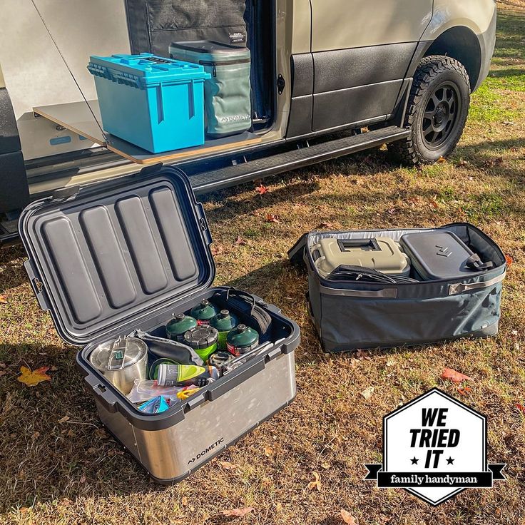 an open suitcase sitting on the ground next to a van with coolers in it