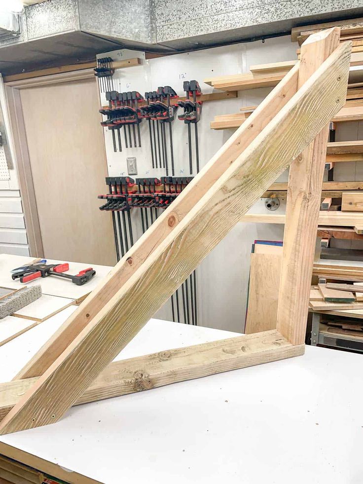 a wooden frame sitting on top of a table next to some woodworking tools and pliers