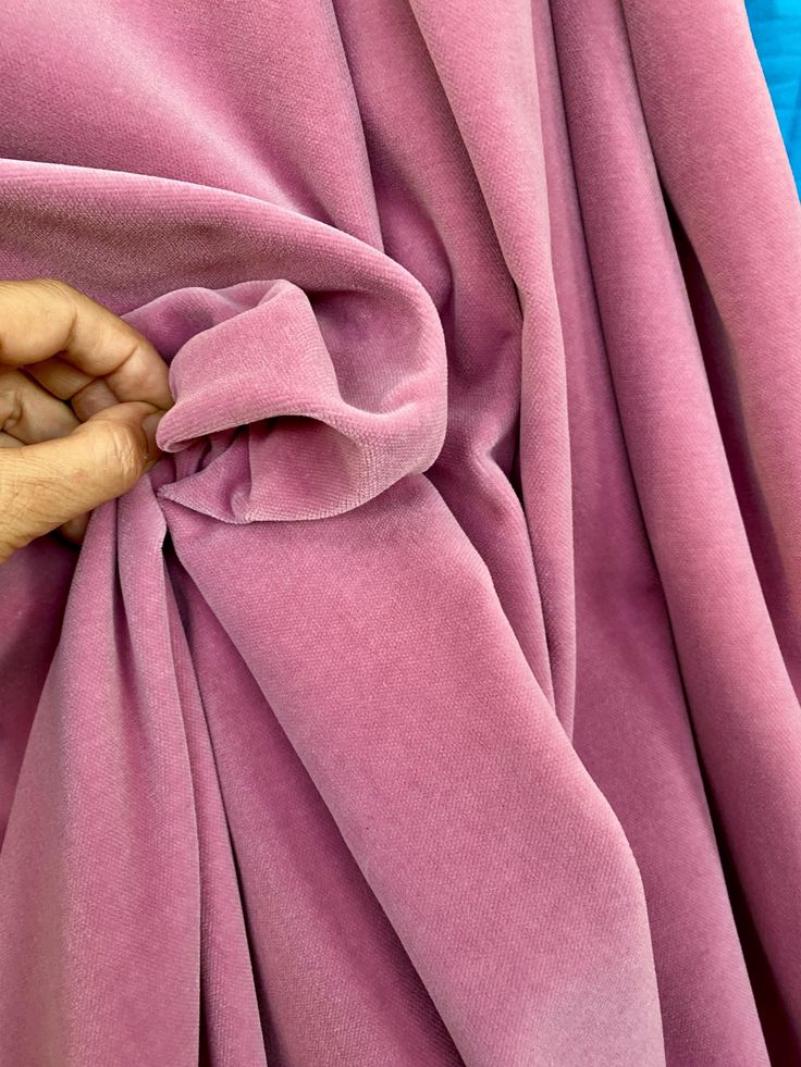 a person's hand holding onto a pink fabric