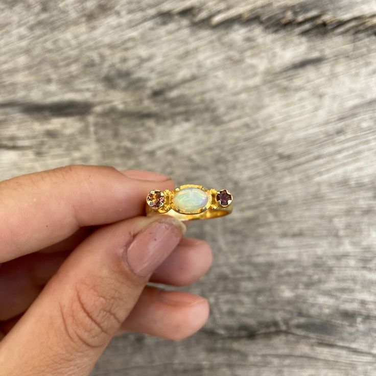 Choose between these gorgeous polished Ethiopian opal rings with amazing sparkles set in sterling silver and then gold plated. The ring has a little different faceted tourmaline on each side of the main stone. Choose between: Blue and yellow- N 1/2 (UK/AU size ring) 6 3/4 (US size) Green and brown- L 1/2 (UK/AU size ring) 5 7/8 (US size) Blue and pink- N 1/2 (UK/AU size ring) 6 3/4 (US size) Pink and brown- M 1/2 (UK/AU size ring) 6 1/4 (US size) This ring would make the most perfect bridesmaid' Fine Jewelry Gold Opal Birthstone Ring, Gold Opal Ring With Birthstone, Gold Opal Birthstone Ring, Fine Jewelry Rings With Ethiopian Opal Birthstone, Fine Jewelry Ethiopian Opal Birthstone Rings, Gold Opal Gemstone Promise Ring, Gold Opal Promise Ring With Gemstone, Gold Opal Gemstone Ring Gift, Gold Opal Crystal Ring For Anniversary