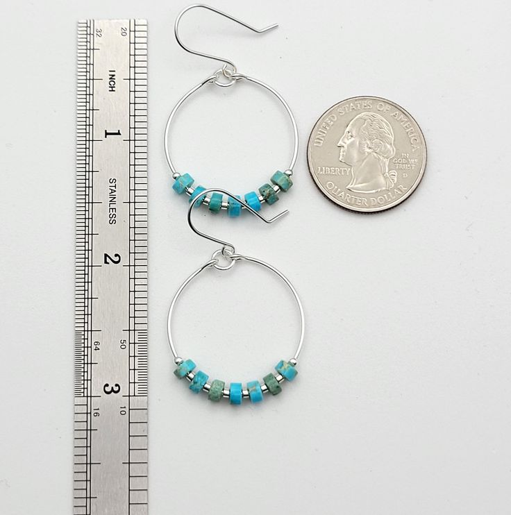 Add a pop of color to your boho look with our silver hoop earrings featuring turquoise jasper stones. These playful and unique earrings will bring a touch of whimsy to any outfit. .925 Sterling Silver Measure approximately 1.125" in diameter Earrings Hang 1.75" from top of ear wire Turquoise Jasper Gemstones Polished to a high shine Sent in a Gift Box with Polishing Cloth Handmade in Montana