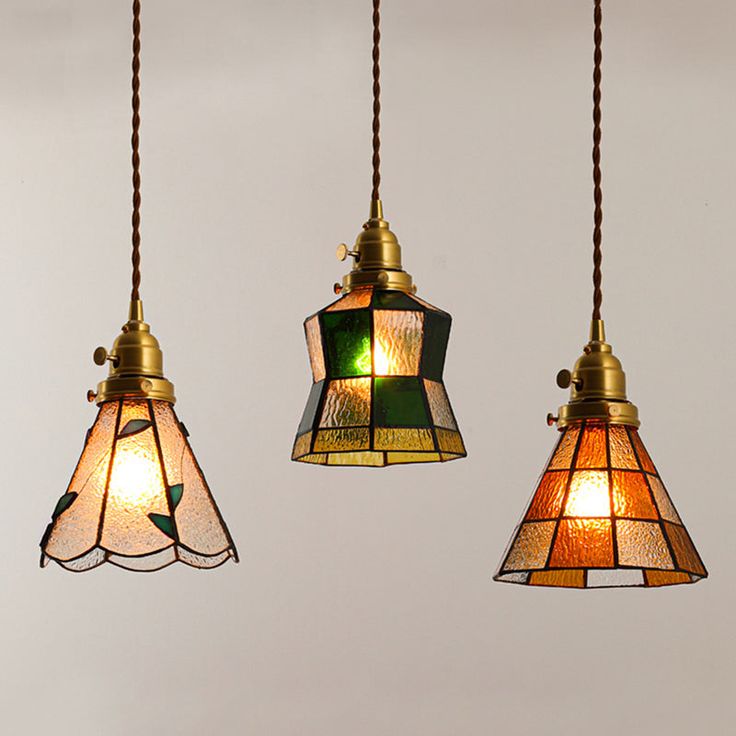 three lamps hanging from the ceiling with one light turned on and two lights off in different colors