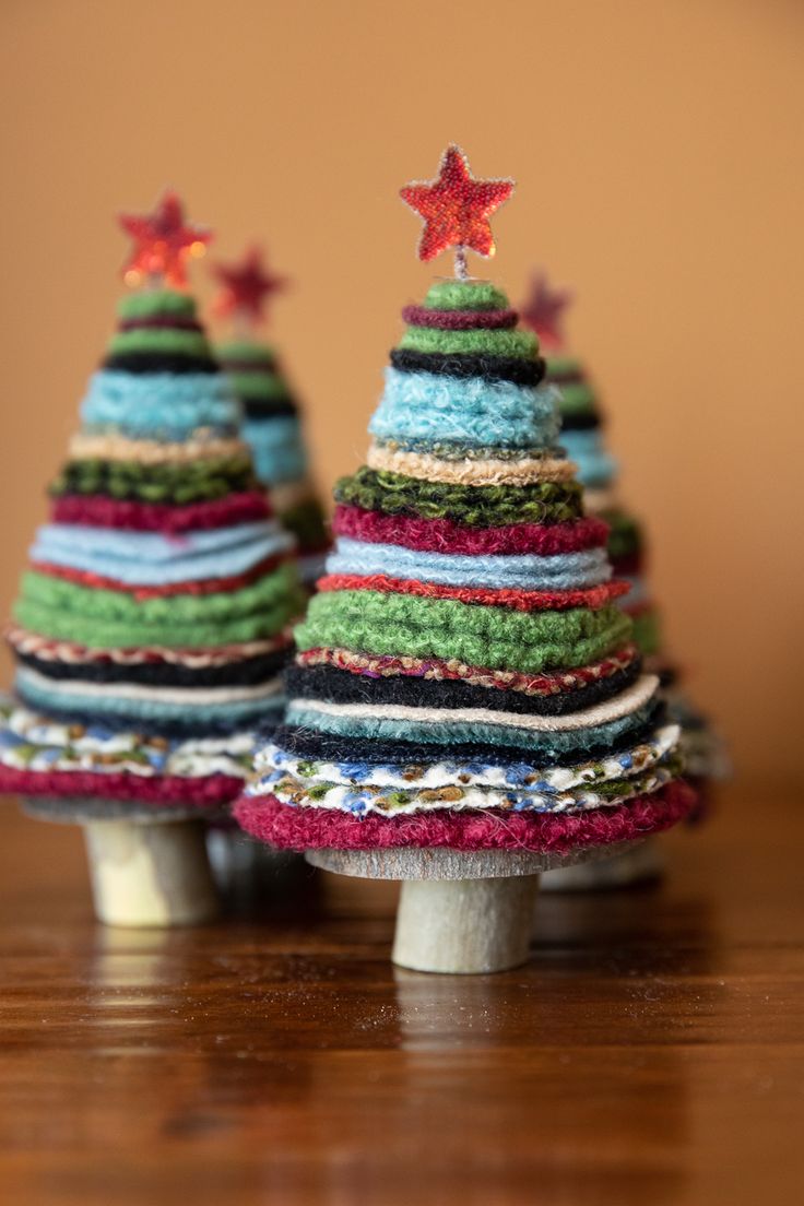 two small christmas trees sitting on top of a wooden table