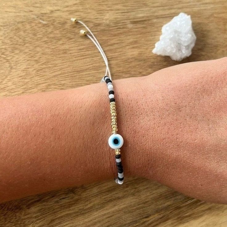 a person's arm with a bracelet and an evil eye beaded on it