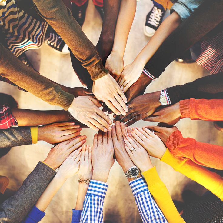 a group of people standing in a circle with their hands on top of each other