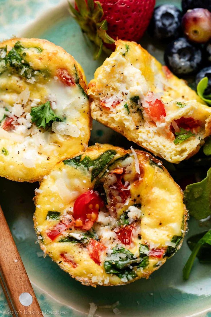 mini muffins filled with cheese and vegetables on a plate next to strawberries