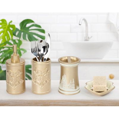 gold bathroom accessories set on counter with sink in background