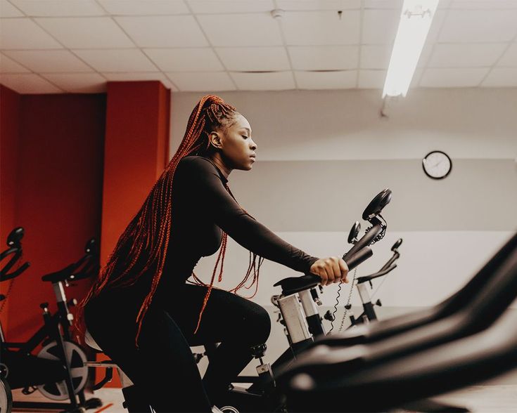 a woman riding a stationary bike in a spinning exercise room with other spin bikes behind her