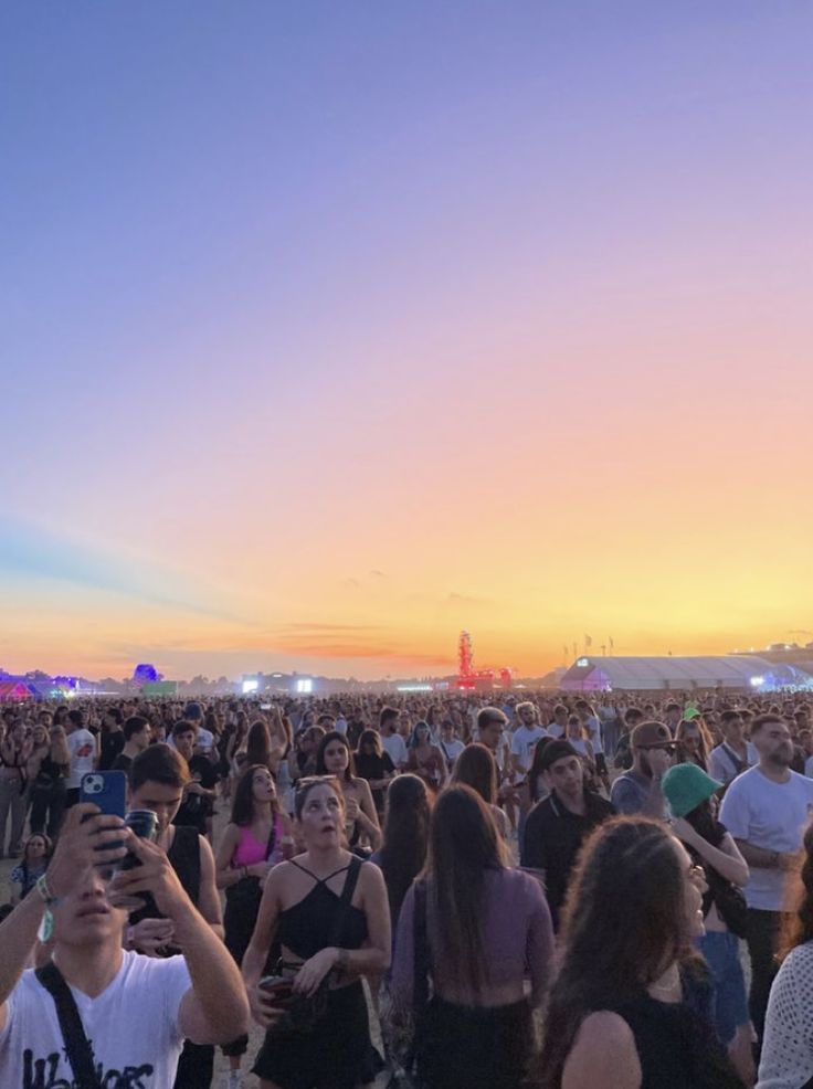 a large group of people standing in front of a crowd at an outdoor music festival