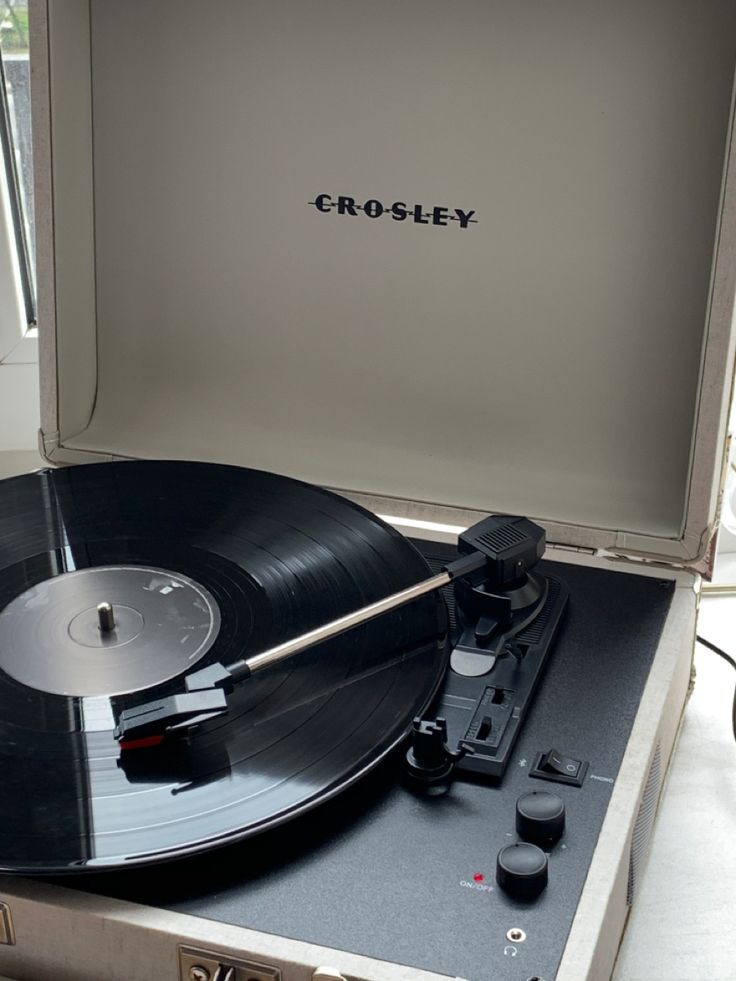 an old record player sitting on top of a suitcase with the word crosley written on it