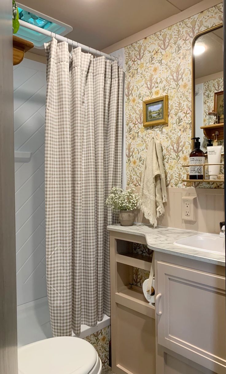 a white sink sitting under a bathroom mirror next to a bath tub and shower curtain