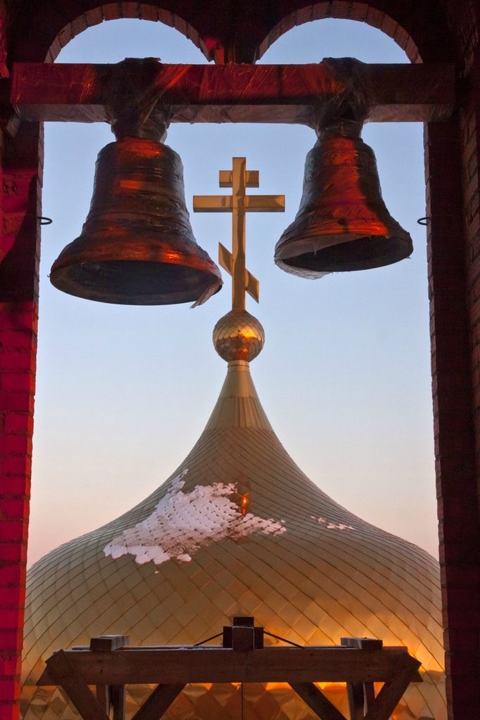 two bells on top of a building with a cross