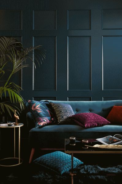 a living room with dark blue walls and colorful pillows on the couch, coffee table