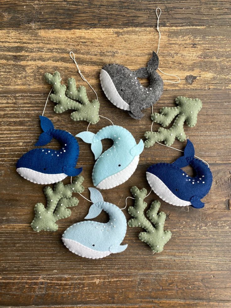 felt whale ornaments are hanging on a wooden table