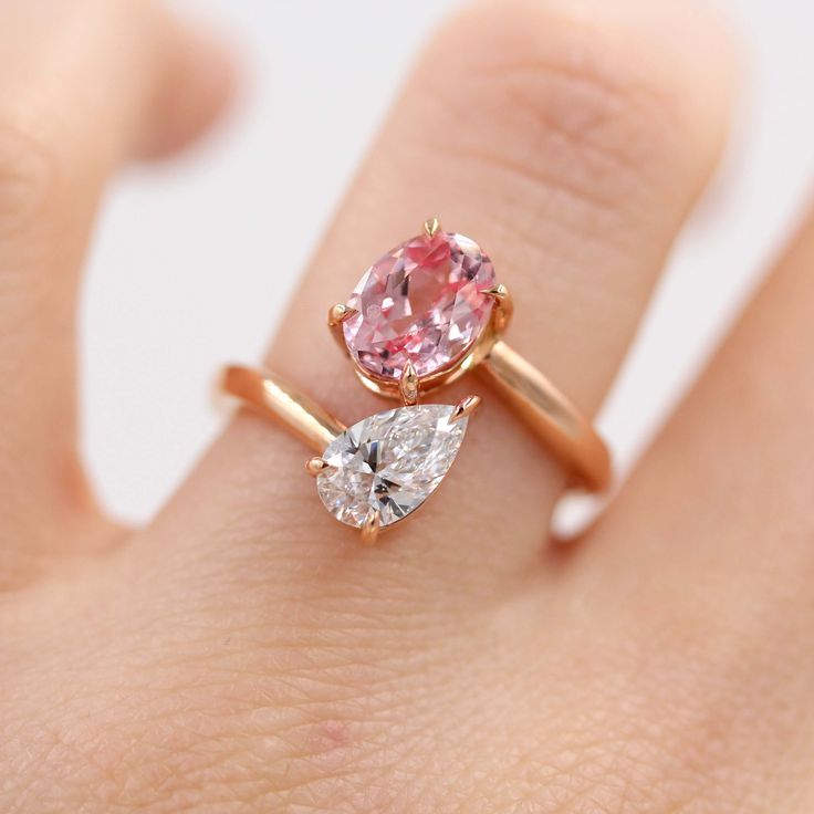 a close up of a person's hand with a pink and white diamond ring