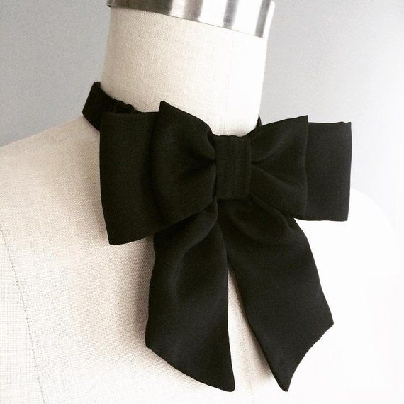 a white mannequin with a black bow tie on it's collar neck