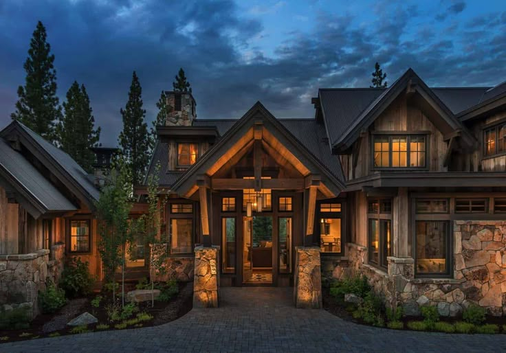 a large house with stone walls and windows at night in front of the entrance to it